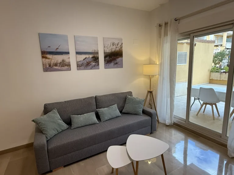 Salón amplio y luminoso con sofá, TV de pantalla plana y acceso directo a la terraza del apartamento turístico en Denia