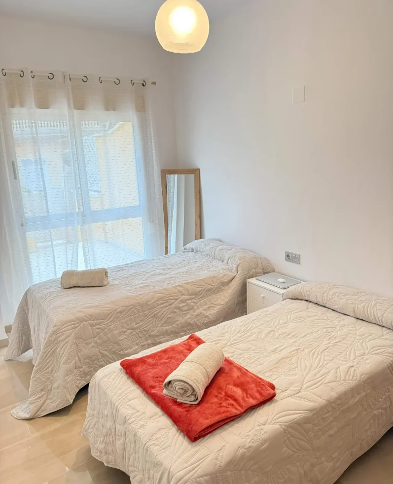 Dormitorio secundario con dos camas individuales y armario, ideal para familias en el apartamento de Denia